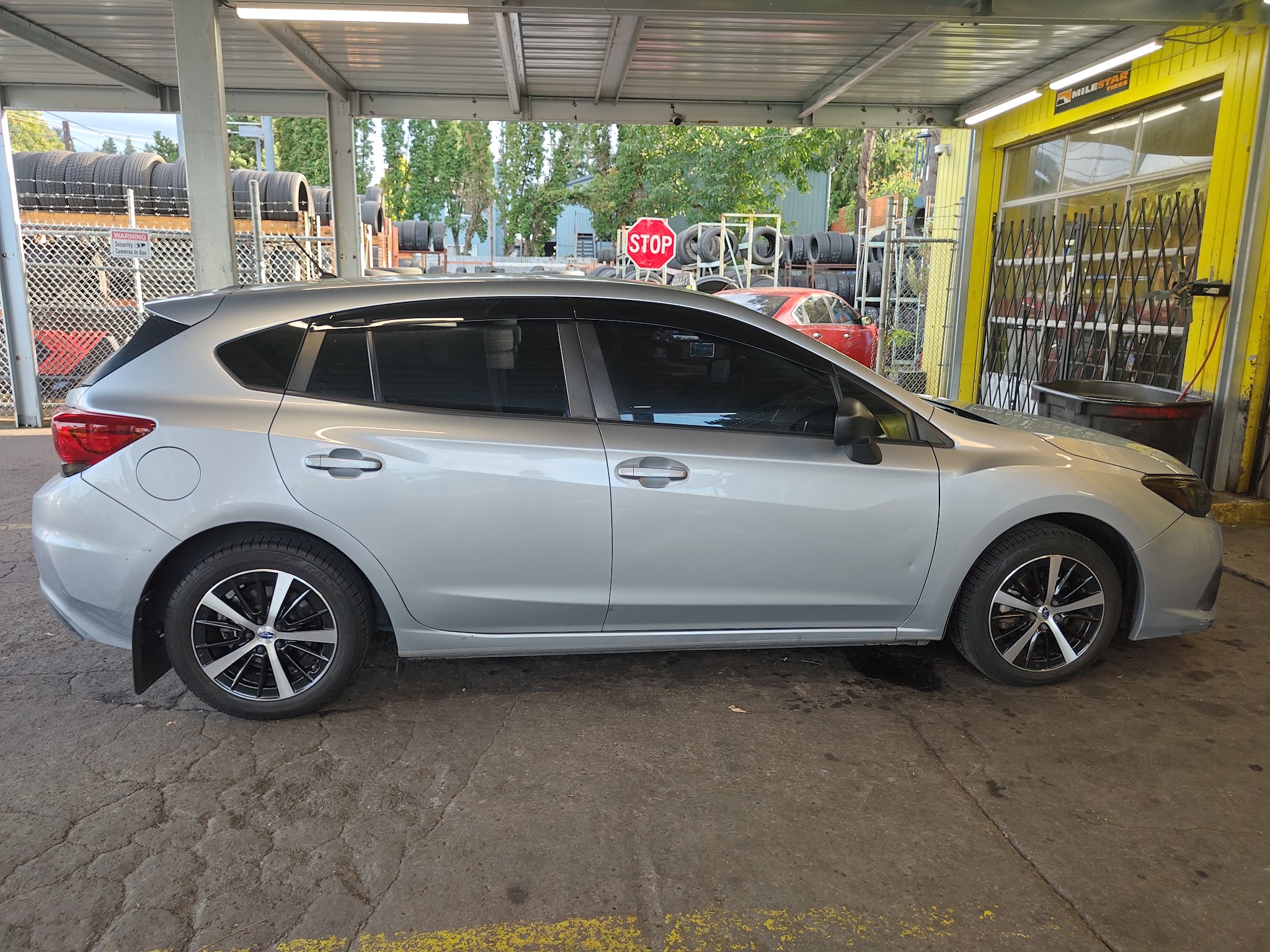 A car parked under the canopy at Portland Tire Shop beside the tire racks