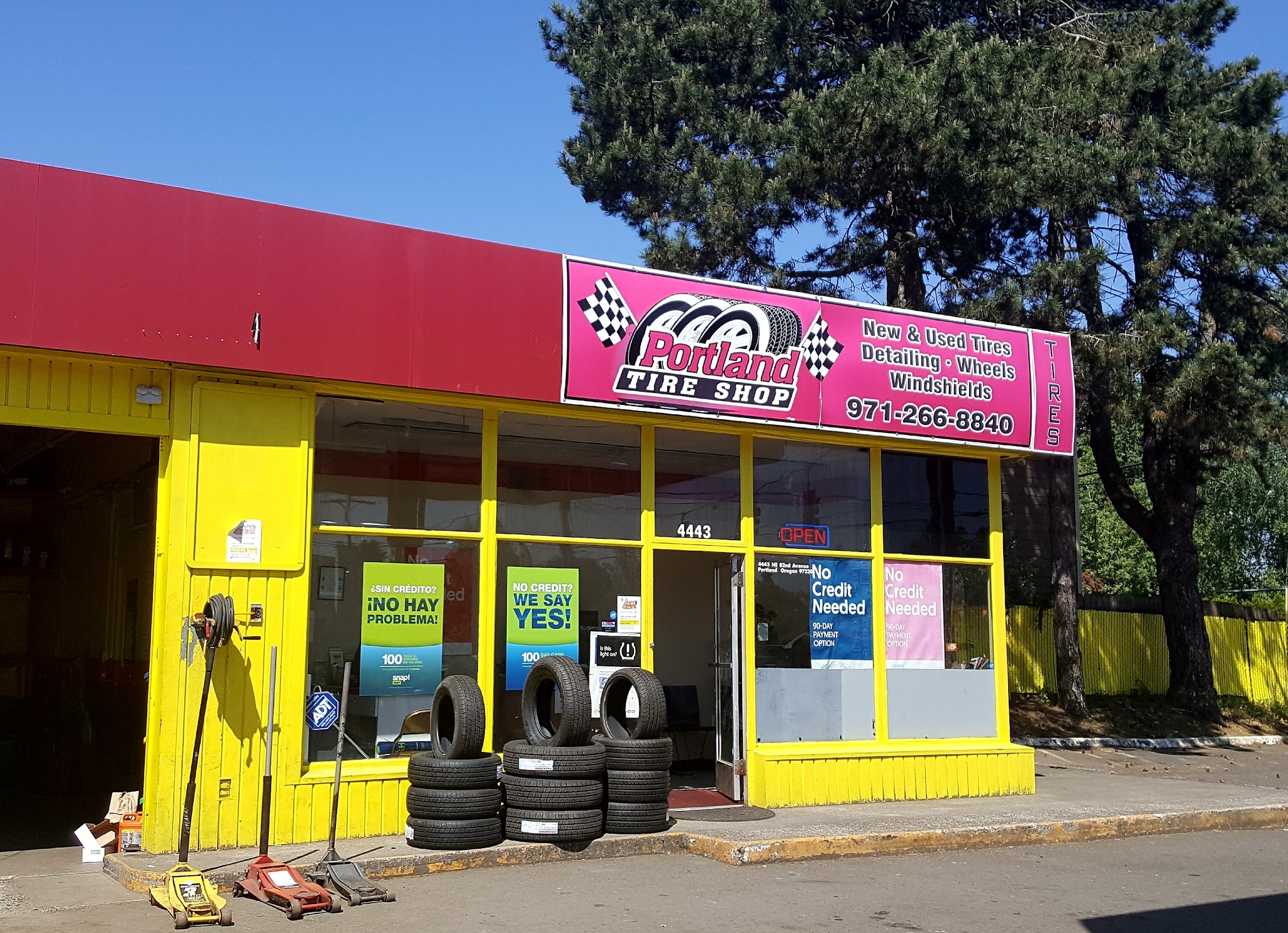 Portland Tire Shop storefront with its no credit needed and payment option signs in the window