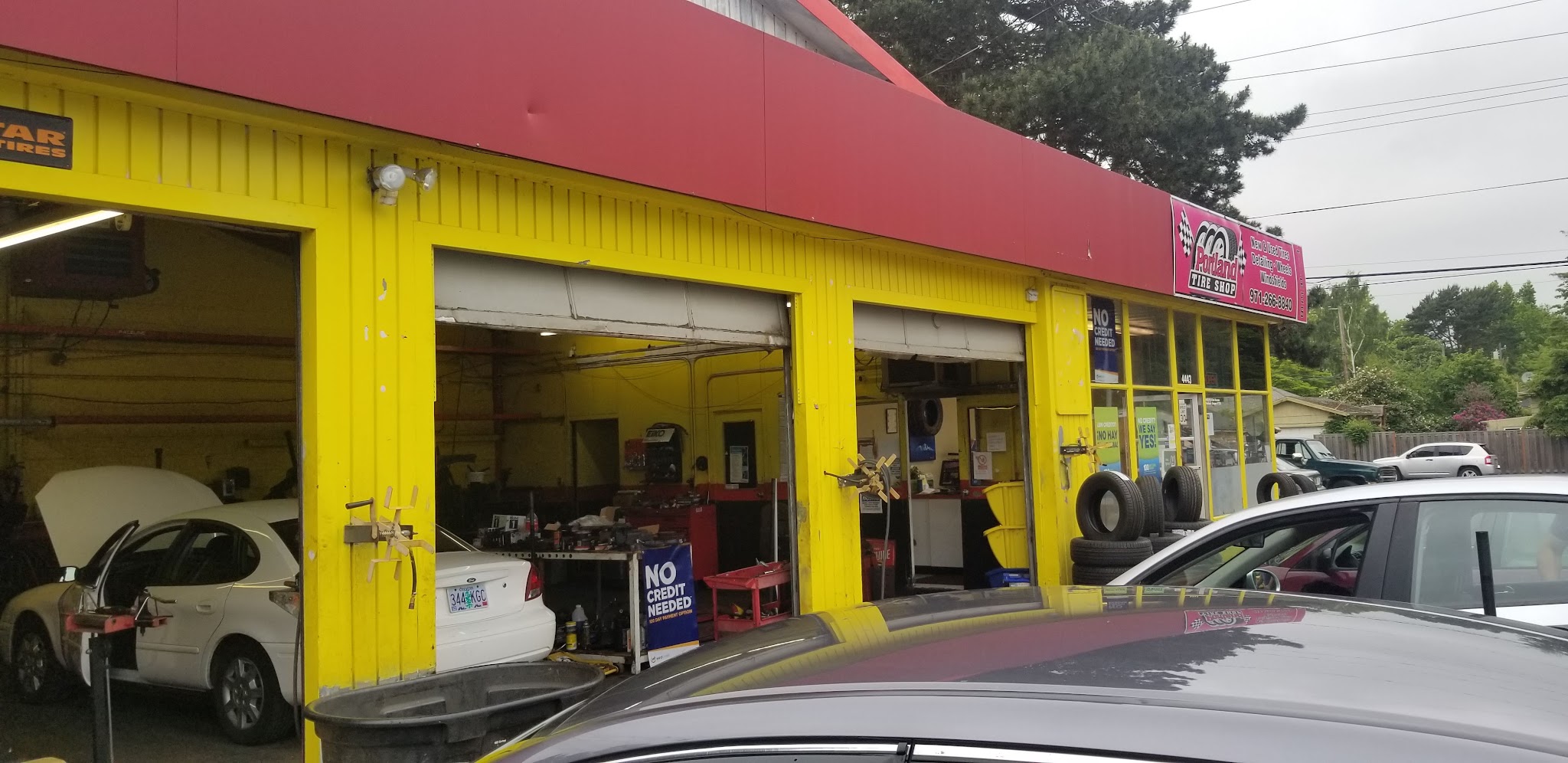 Open service bays at Portland Tire Shop with cars being worked on